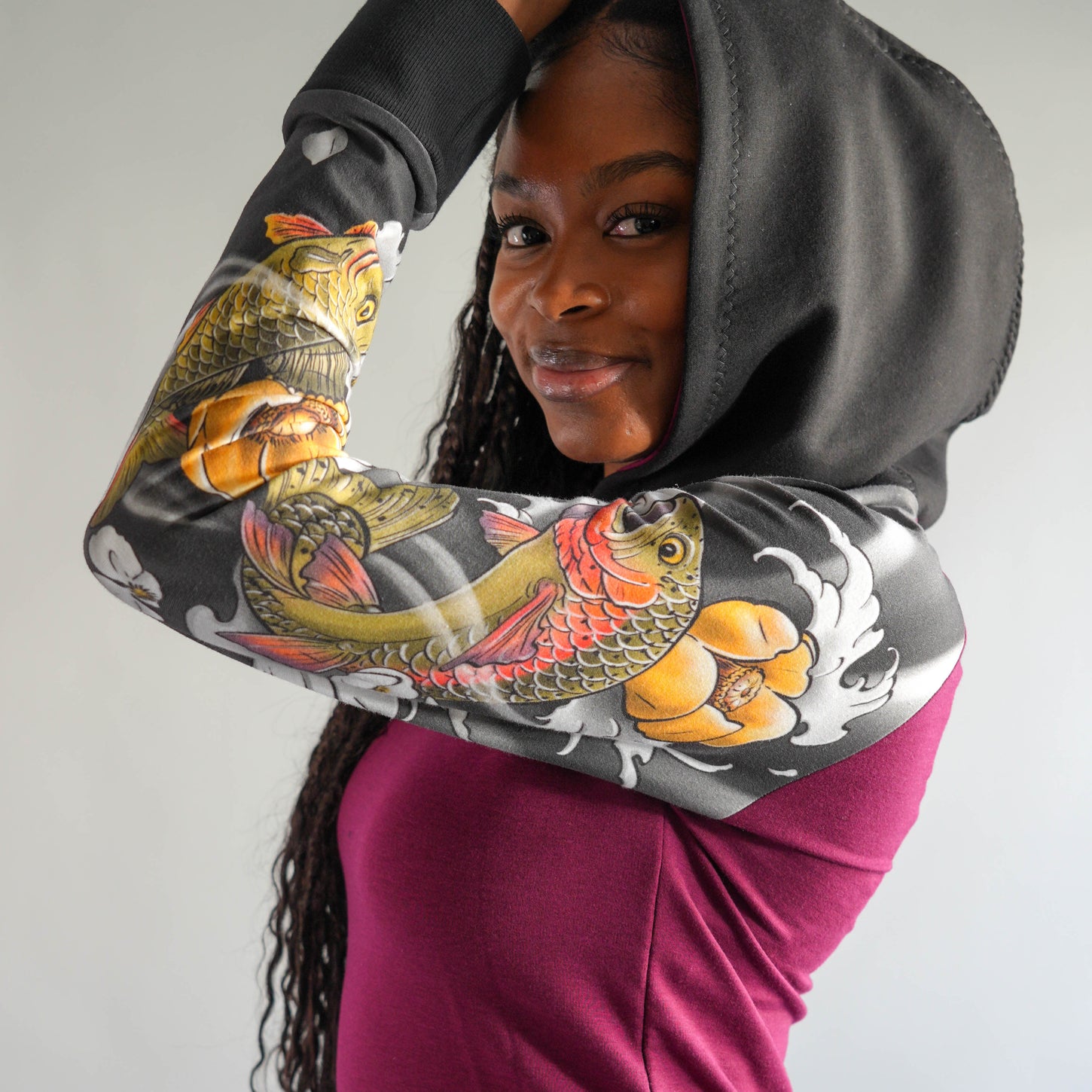 Person wearing a hoodie with a colorful fish design on a plain background